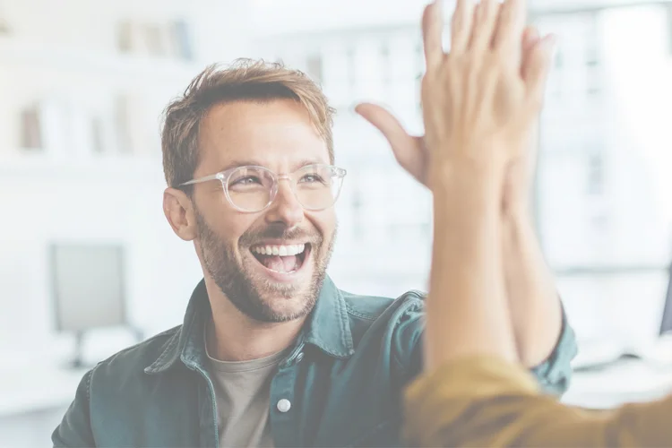 Mann mit Brille macht ein "High 5" mit einer Frau